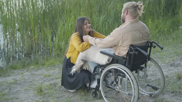 Paraplegic Caucasian Man Sitting in Wheelchair and Touching Black Hair of Smiling Woman. Portrait of