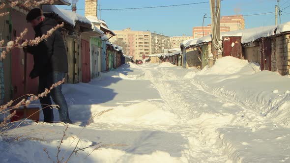 A Man Cuts Snow Into Large Pieces with a Shovel and Throws Them Away