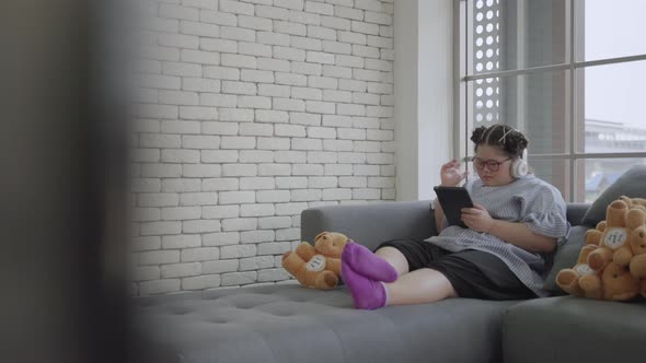 young Asian girl with Down's syndrome is playing a tablet alone in the room