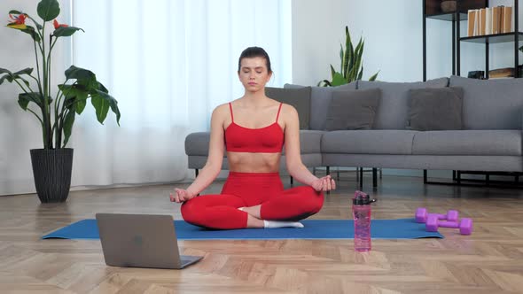 Beautiful Fit Girl Sits Meditating in Lotus Position on Sport Fitness Blue Mat