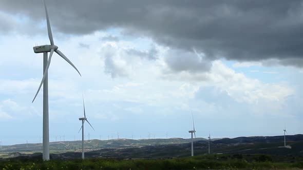 Dark Clouds in Stormy Sky Over Wind Farm, Turbine Blades Rotate, Weather Change