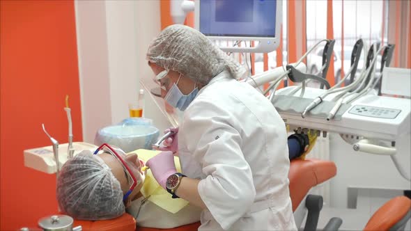 Female Professional Dentist at Work Doing Dental Treatment. Installs a Seal. Dental Examination