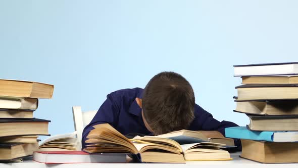Boy Sits at the Table and Falls Asleep for a Book. Blue Background