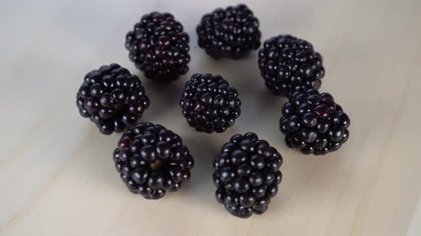 A pile of blackberry berries rotates on a wooden background