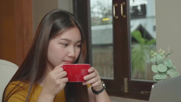 Beautiful Young Asian Woman Drinking Hot Coffee And Looking Laptop In Café