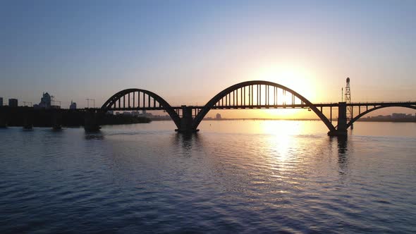 Beautiful sunset, sunrise over the river. Dark silhouette of the arch bridge. Dnipro, Ukraine.
