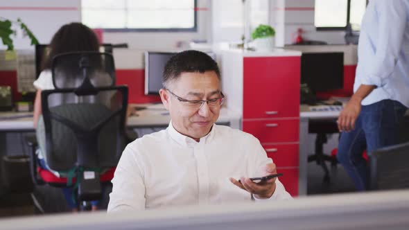 Senior businessman talking on his smartphone and celebrating his success in office in slow motion