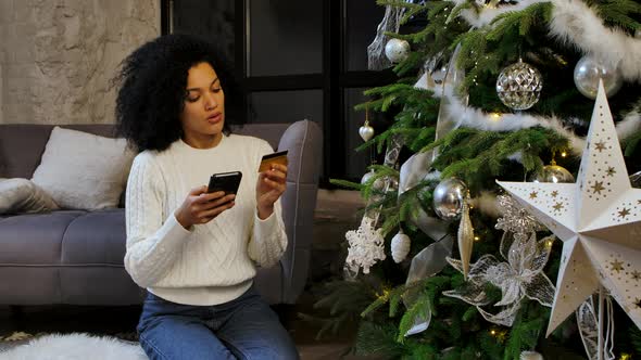 Portrait of a Happy African American Woman Making an Online Purchase Using Her Smartphone and Credit