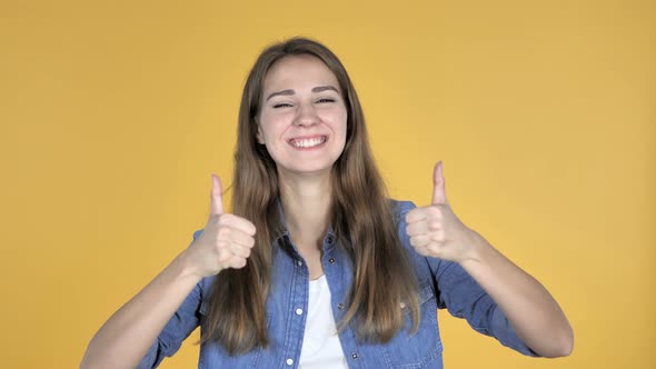 Pretty Woman Gesturing Thumbs Up Isolated on Yellow Background