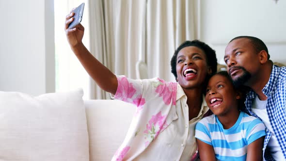 Family taking selfie on mobile phone in living room