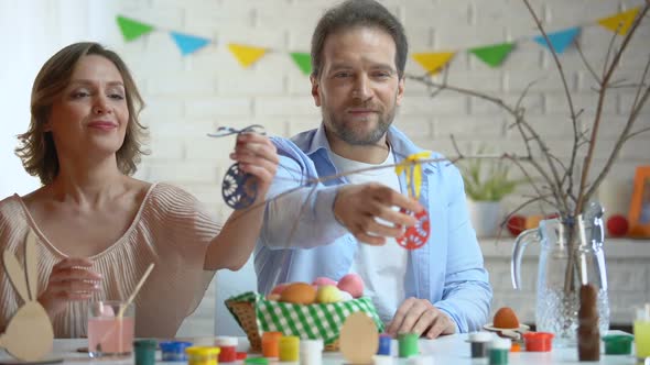 Husband and Wife Preparing Easter Decoration, Hanging Toy Eggs on Tree-Branch