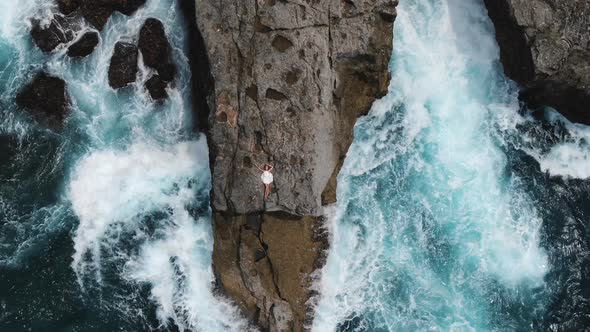 Woman in a White Short Dress Lies on the Edge of a Cliff