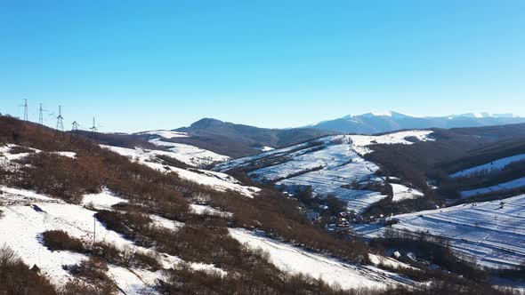 High Voltage Power Lines in the Mountains in Winter Aerial View