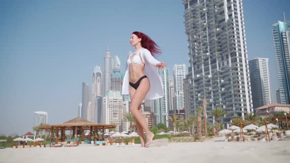 Slim Woman in Swimsuit is Spinning with Happiness on the Beach in Dubai