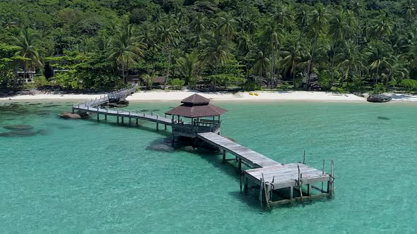 Drone circling around wooden footbridge leading into the sea. Koh Kood, Thailand.