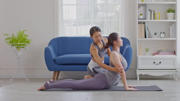 Yoga trainer helping asian woman doing yoga exercise Cobra pose