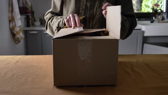 woman unpacking a box of cosmetics in the kitchen at home