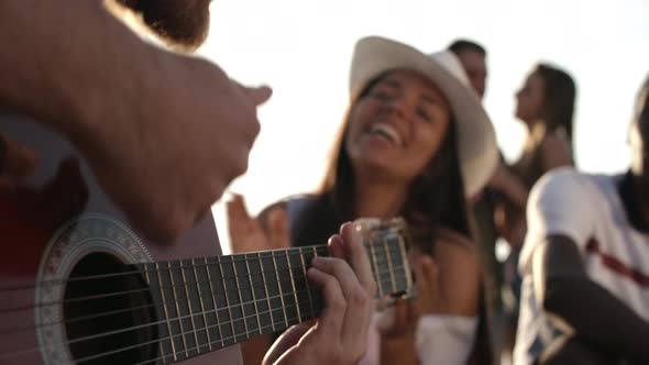 Man Playing Guitar for Friends Outdoors