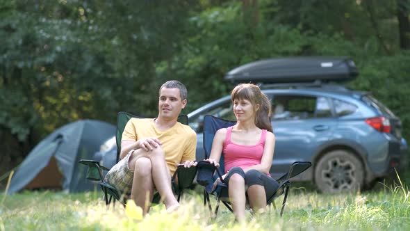 Young Couple Sitting Near Campsite Talking Happily Enjoying Time Together