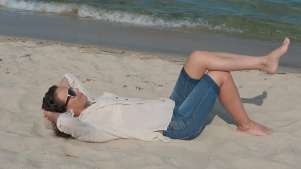 Happy woman is lying on the sand at the beach.