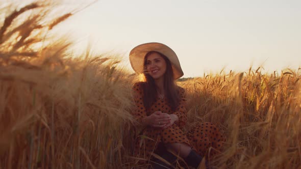 Pregnant woman in the rays of the sunset in the field