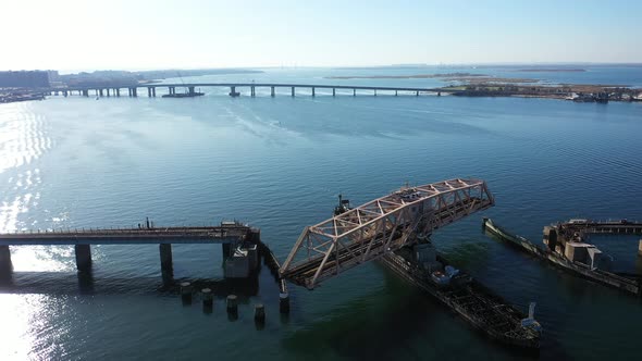 An aerial drone shot over Grassy Bay in Queens, NY. The camera hover by train tracks as the swing br