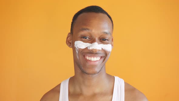 African-American Man Smiles at the Camera on an Isolated Yellow Background, He Uses a Nourishing