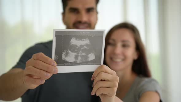 The happiness of a pregnant woman and her husband with the ultrasound film