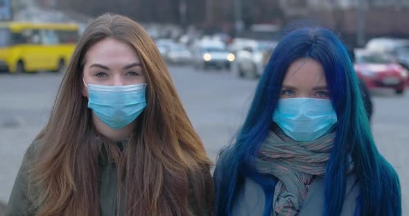 Portrait of Brunette and Blue-haired Girls Wearing Protective Masks. Young Women Standing Outdoors