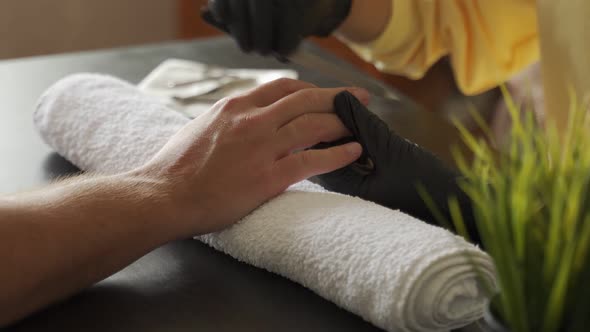 Manicurist Using a File on a Fingernail to Remove Excess Cuticles and Prepare It for Painting