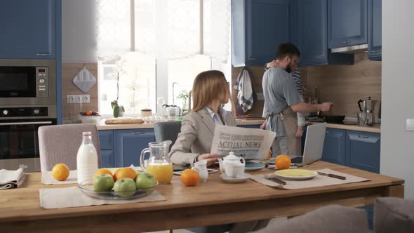 Caucasian Businesswoman Waiting for Breakfast and Husband Cooking