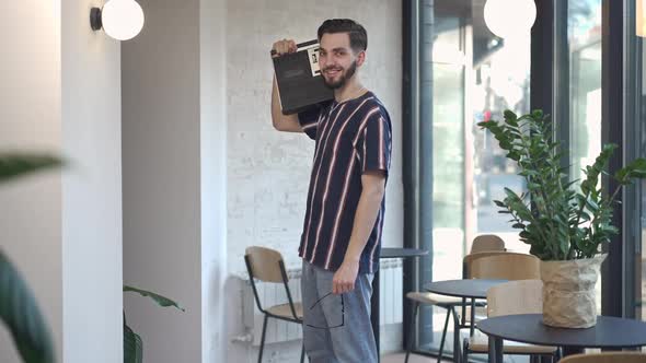 Live Camera Zoom in to Smiling Confident Young Man Posing with Vintage Tape Recorder on Shoulder