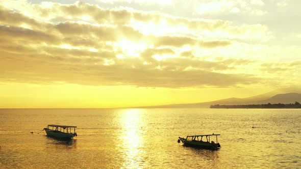 The beautiful glow of the sunset reflected into the water with small boats sitting on the surface