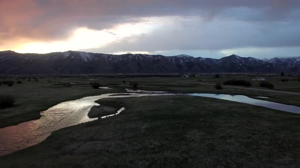 Flying view over bend in river as sun is lighting up clouds