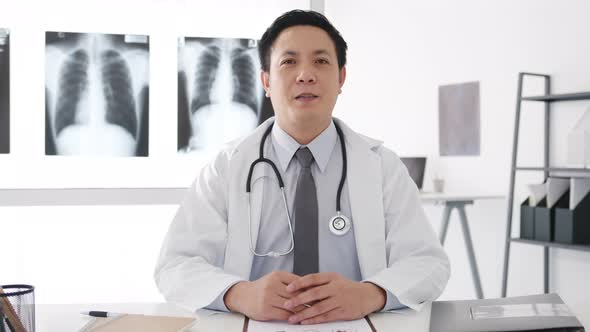 young Asia male doctor with stethoscope looking at camera and smiling while video conference call.