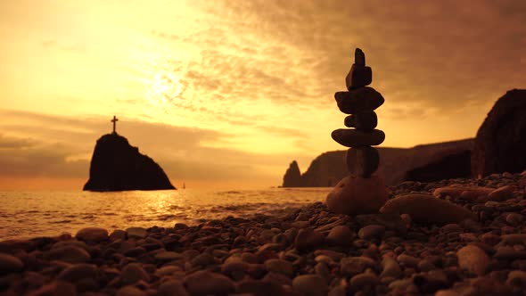 Pyramid Stones on the Seashore with Warm Sunset on the Sea Background