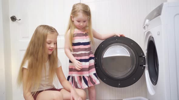 Cute Little Girls Open the Door and Put Laundry in the Washing Machine