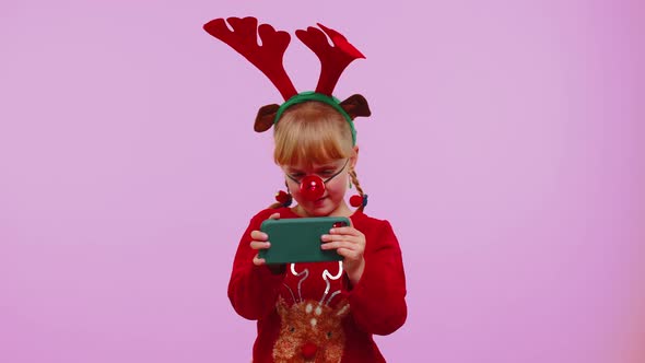 Worried Girl in Christmas Deer Antlers Enthusiastically Playing Racing Video Games on Mobile Phone