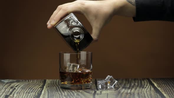 Pouring Whiskey, Cognac Into Glass. Dark Background. Pour of Alcohol Drink