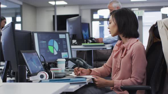 Woman taking notes while sitting on her desk at home