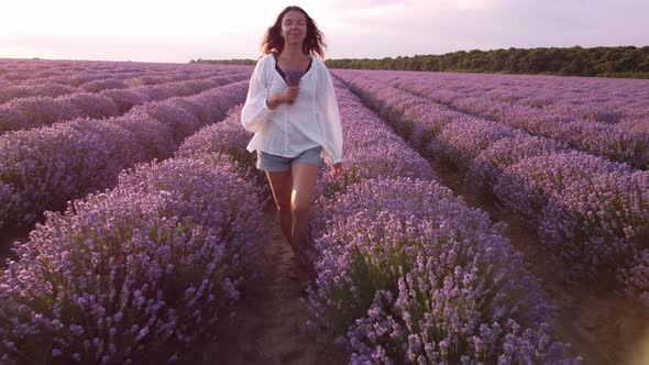 Young Woman in White Shirt Walking in Beautiful Lavender Field