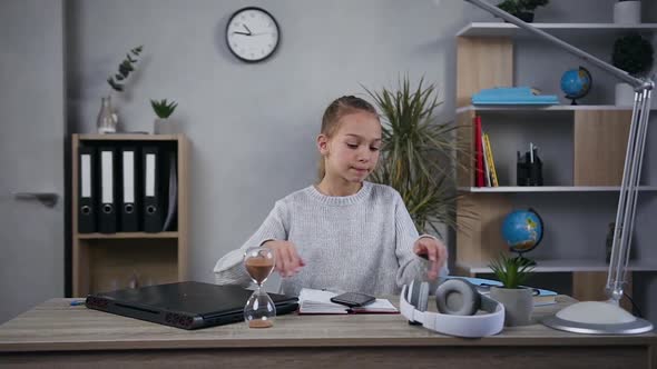 Girl in Knitted Sweater Listening Music in Headphones After Her Work on the Computer