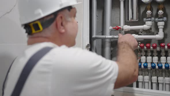 Plumber Carries Out Work in the House and Opens the Water in the Water Distribution Panel