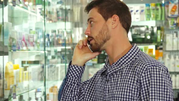 Man Talking on Phone About Pills in Drugstore