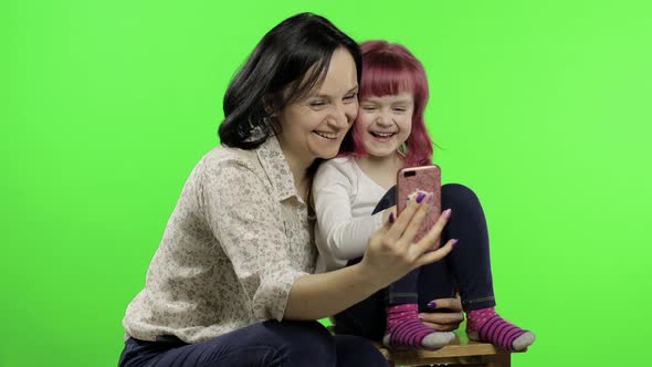 Mother, Daughter Holding, Using Smart Phone Talking on Video Call. Social Media