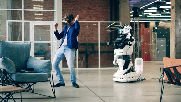 A Man in VRglasses is Dancing with a Modern Robot