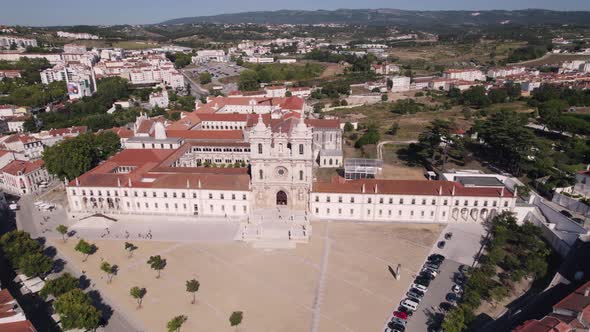 Aerial pull out shot reveals spectacular Alcobaça Monastery catholic monastic complex and cityscape.