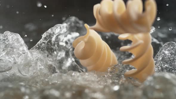 Throwing fusilli spiral pasta in water. Slow Motion.
