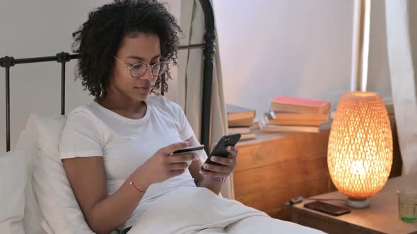 Online Payment Success on Smartphone By Young African Woman in Bed 