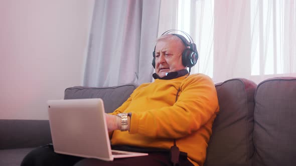 Excited Elderly Man with Headset Gambling Online and Winning